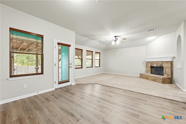 unfurnished living room featuring a fireplace, light wood-type flooring, ceiling fan, and plenty of natural light