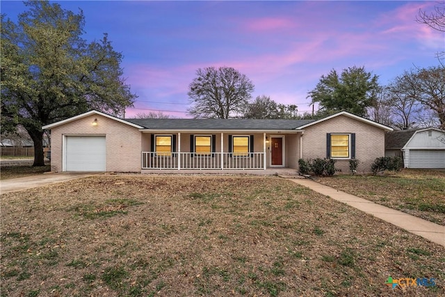 single story home featuring an attached garage, covered porch, brick siding, driveway, and a front yard