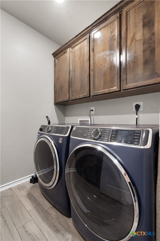 laundry room with light hardwood / wood-style flooring, cabinets, and washer and dryer