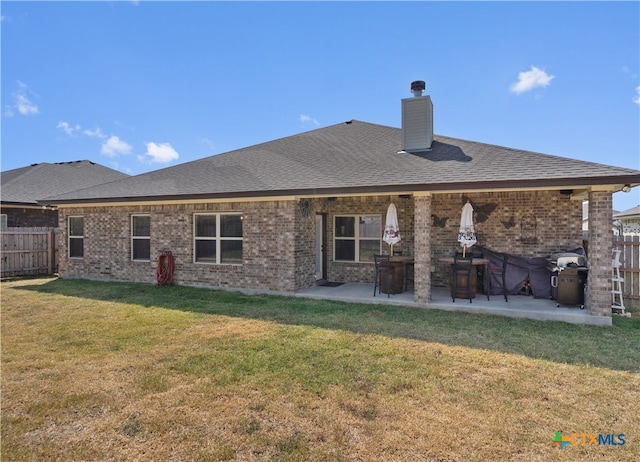 rear view of property featuring a patio and a yard