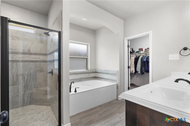 bathroom featuring vanity, plus walk in shower, and wood-type flooring