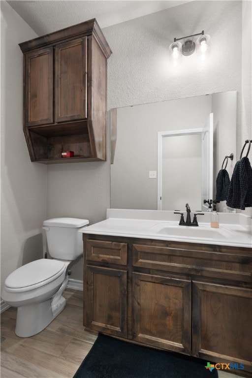 bathroom with hardwood / wood-style floors, vanity, and toilet