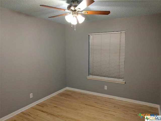 spare room featuring a textured ceiling, ceiling fan, baseboards, and wood finished floors