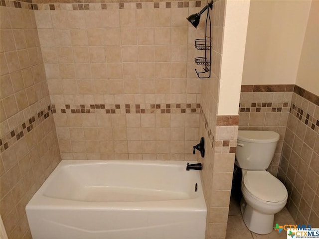 bathroom featuring wainscoting, shower / bathing tub combination, toilet, and tile walls
