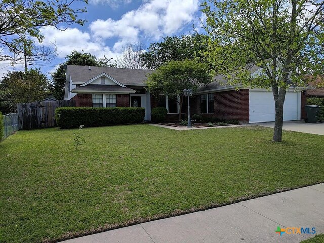 ranch-style house featuring brick siding, a front lawn, fence, and driveway
