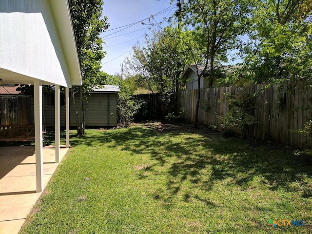 view of yard featuring a patio, a fenced backyard, and an outdoor structure