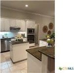 kitchen featuring light tile patterned floors, dark countertops, ornamental molding, dishwasher, and a peninsula