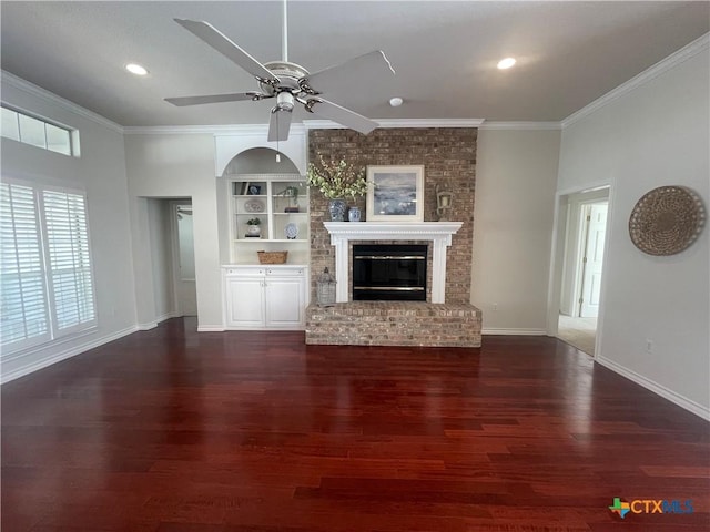 unfurnished living room with a brick fireplace, baseboards, ornamental molding, and wood finished floors