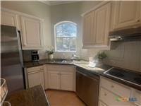 kitchen with dark countertops, under cabinet range hood, appliances with stainless steel finishes, and cream cabinetry