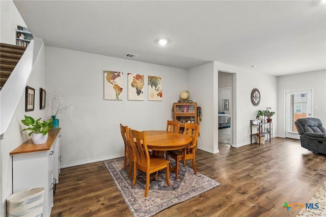 dining area with stairs, wood finished floors, visible vents, and baseboards