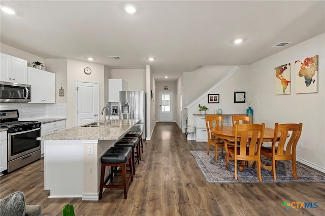 kitchen featuring stainless steel appliances, dark wood finished floors, a sink, and a kitchen breakfast bar