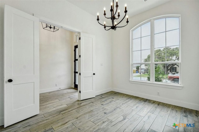 unfurnished dining area featuring a chandelier and light wood-type flooring