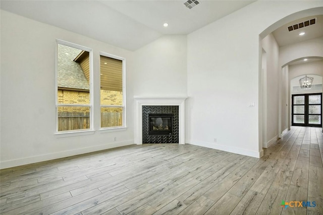 unfurnished living room with light wood-type flooring, vaulted ceiling, and a healthy amount of sunlight