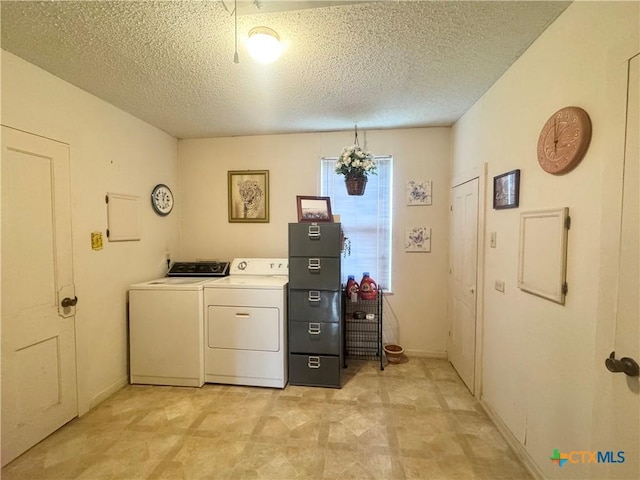 clothes washing area with baseboards, washer and dryer, laundry area, and a textured ceiling