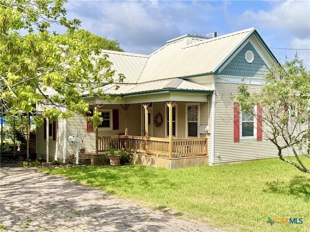 view of front of property with a porch, metal roof, and a front yard