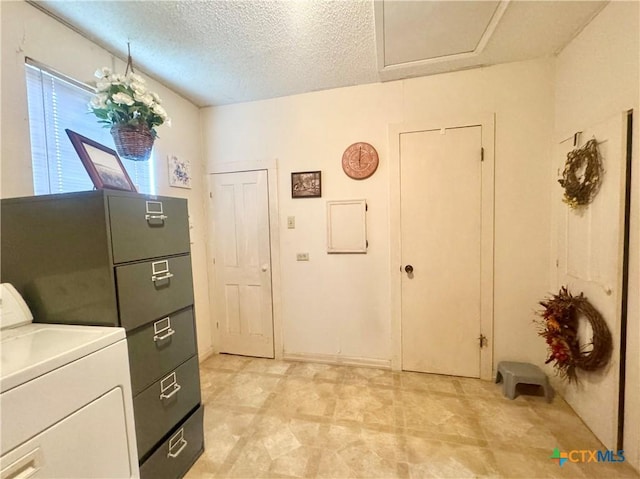 clothes washing area with washer / clothes dryer and a textured ceiling