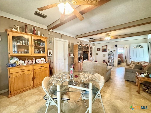 dining room featuring beamed ceiling, a ceiling fan, and visible vents