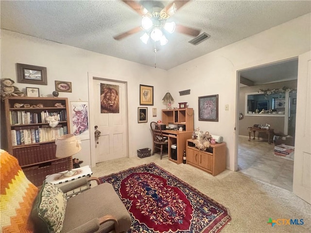 office area with visible vents, a textured ceiling, a ceiling fan, and carpet floors