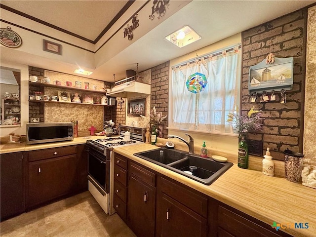 kitchen featuring white range with gas cooktop, dark brown cabinetry, stainless steel microwave, light countertops, and a sink