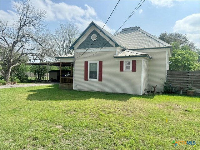 view of side of property with metal roof, fence, and a lawn