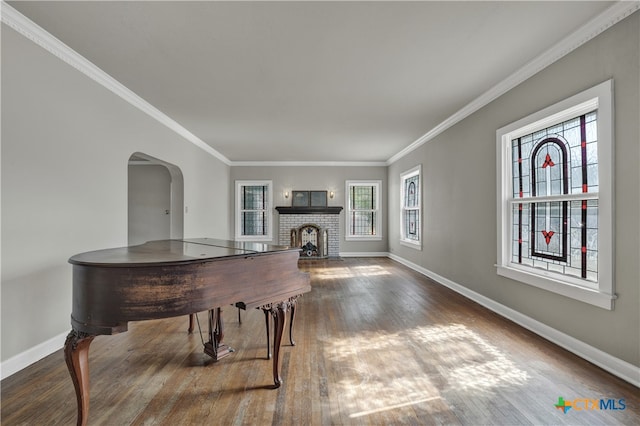 game room with dark hardwood / wood-style flooring, ornamental molding, and a brick fireplace