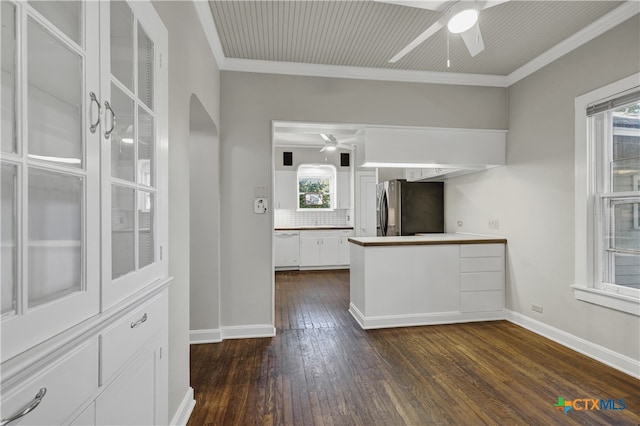 kitchen with white cabinets, ornamental molding, dark hardwood / wood-style floors, ceiling fan, and stainless steel refrigerator