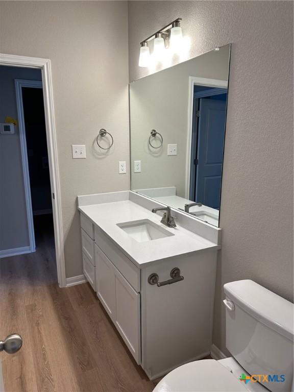 bathroom with vanity, hardwood / wood-style flooring, and toilet