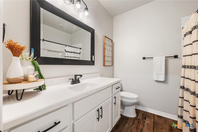 bathroom featuring curtained shower, toilet, wood finished floors, vanity, and baseboards