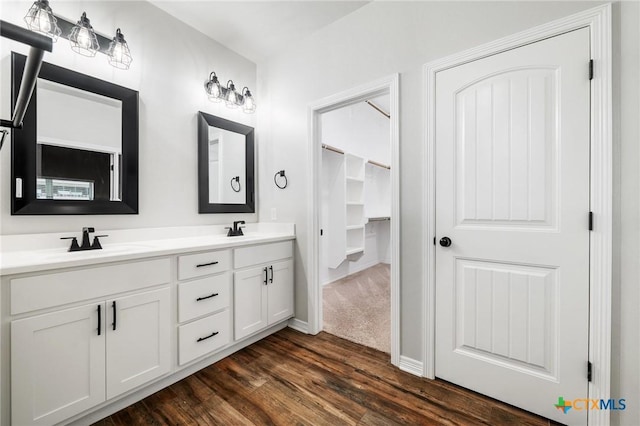 full bath with double vanity, wood finished floors, a sink, and baseboards