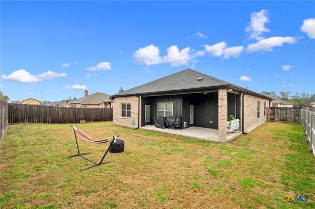 rear view of property with a patio area, a fenced backyard, a yard, and brick siding