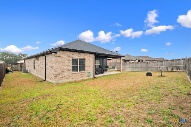 rear view of property with a fenced backyard, a yard, brick siding, and a patio