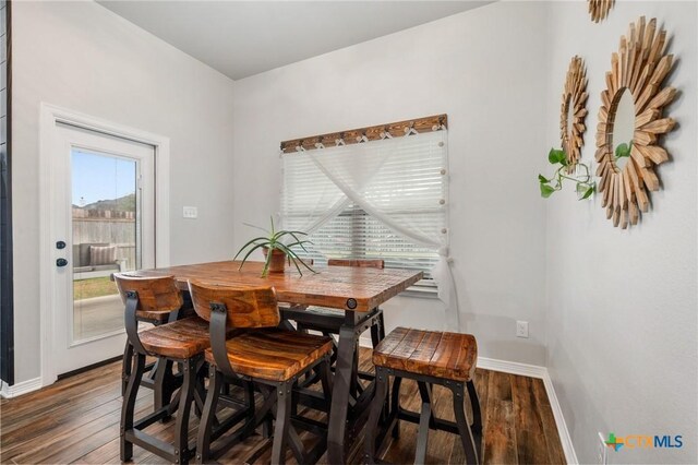 dining area with baseboards and dark wood finished floors