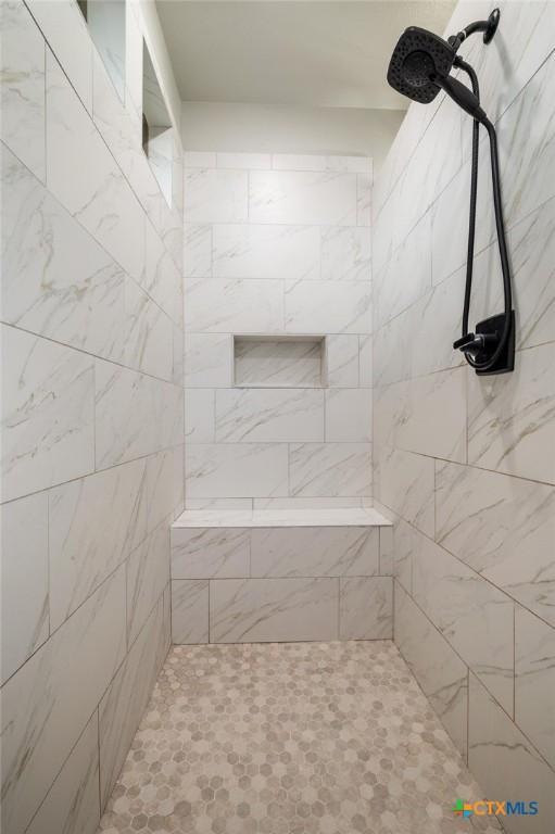 bathroom with double vanity, baseboards, wood finished floors, a walk in shower, and a sink