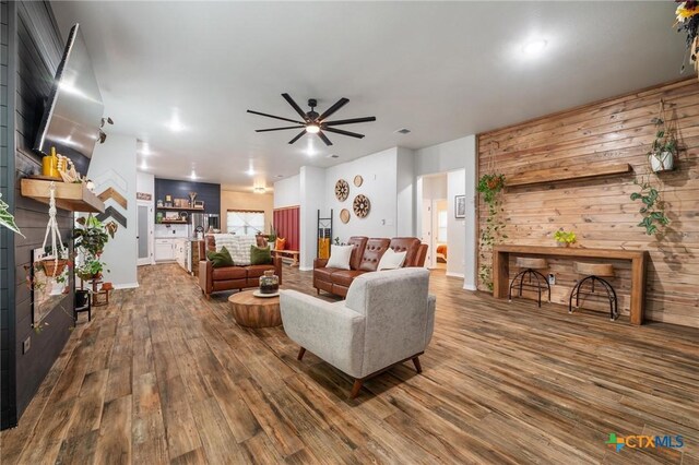 living area featuring ceiling fan, visible vents, baseboards, and wood finished floors