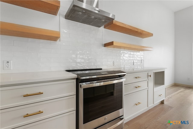 kitchen featuring extractor fan, light hardwood / wood-style flooring, white cabinets, decorative backsplash, and electric stove