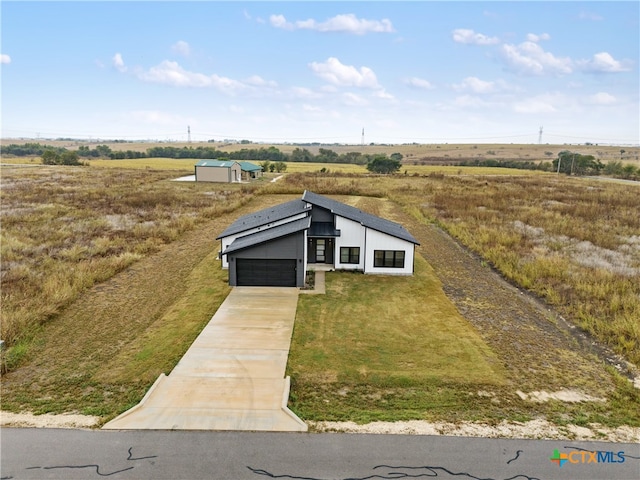 view of front facade featuring a front lawn, a garage, and a rural view