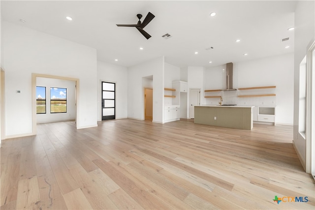 unfurnished living room with light hardwood / wood-style flooring and ceiling fan