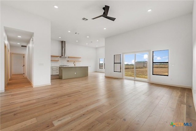 unfurnished living room featuring light hardwood / wood-style floors, ceiling fan, and sink