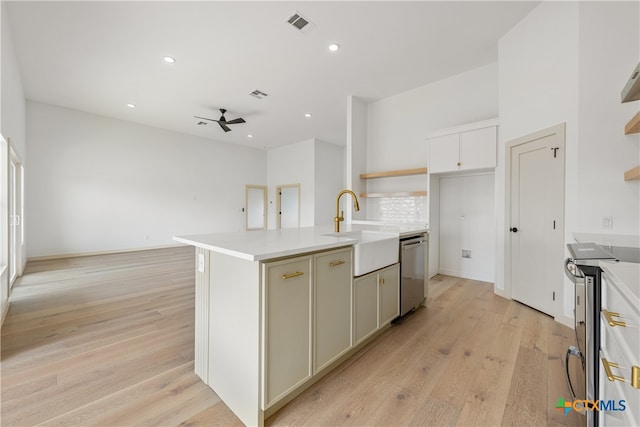 kitchen featuring stainless steel appliances, a center island with sink, sink, ceiling fan, and light hardwood / wood-style flooring