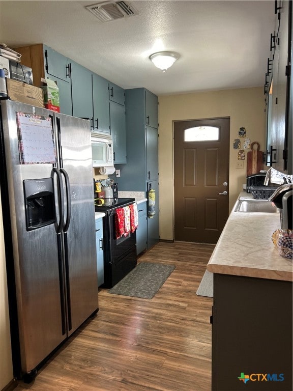 kitchen featuring blue cabinetry, sink, dark hardwood / wood-style flooring, black electric range, and stainless steel fridge