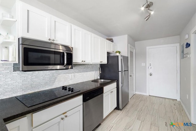 kitchen with stainless steel appliances, white cabinetry, tasteful backsplash, and sink