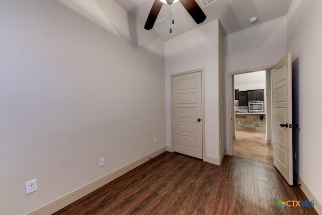 unfurnished bedroom featuring a towering ceiling, ceiling fan, and dark hardwood / wood-style floors