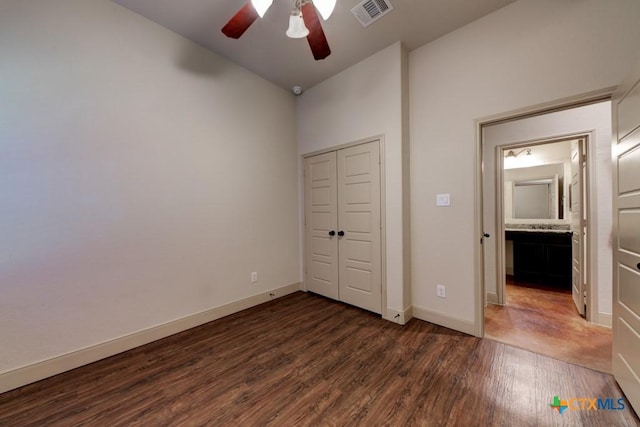 unfurnished bedroom featuring dark wood-type flooring, ceiling fan, a closet, and connected bathroom