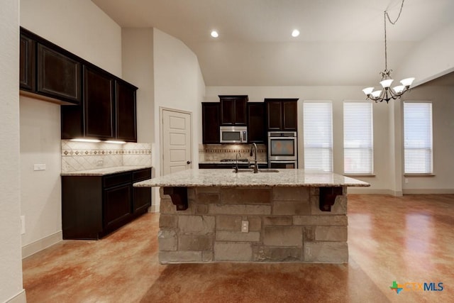 kitchen featuring stainless steel appliances, sink, vaulted ceiling, an island with sink, and decorative backsplash