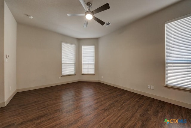 empty room with a healthy amount of sunlight, ceiling fan, and dark hardwood / wood-style flooring