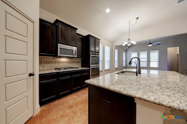 kitchen with backsplash, a center island with sink, stainless steel appliances, sink, and lofted ceiling