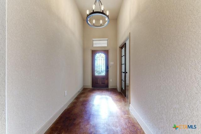 doorway to outside with a high ceiling, concrete floors, and an inviting chandelier