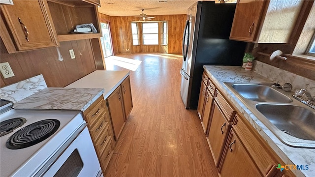 kitchen featuring white range with electric stovetop, a textured ceiling, wooden walls, and light hardwood / wood-style flooring