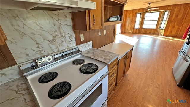 kitchen featuring ventilation hood, white electric range oven, wood walls, and light wood-type flooring