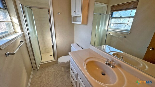 bathroom featuring tile patterned flooring, vanity, toilet, and walk in shower